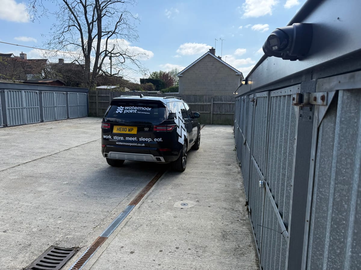 A lock-up garage with a vehicle parked alongside and CCTV overhead